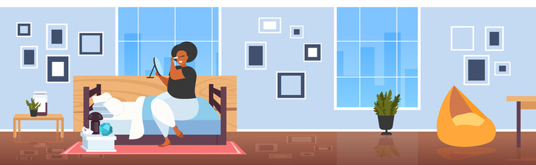 fat obese woman applying black mascara african american girl looking at mirror touching eyelashes using tassel making professional make up modern bedroom interior flat full length horizontal
