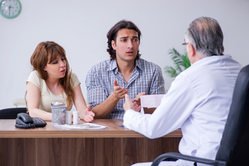 Young couple visiting old male doctor