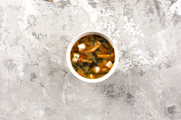 Japanese food. Miso soup with seaweed, mushrooms and tofu. On a texture background.