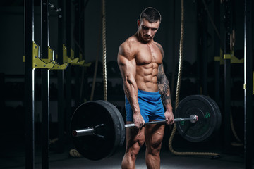 Fototapeta na wymiar Muscular man bodybuilder prepares for lifting heavy barbell in gym. Fit muscle guy workout with weights and barbell. Concept sport photo