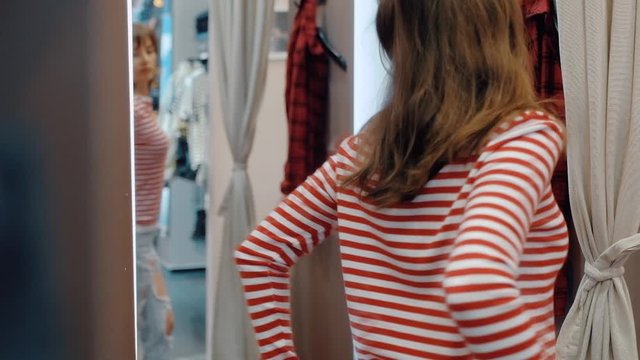 Slim beautiful young woman tries on stylish full-bodied jeans