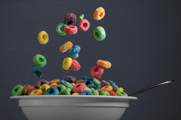 Colorful round cereal in mid air being poured into bowl