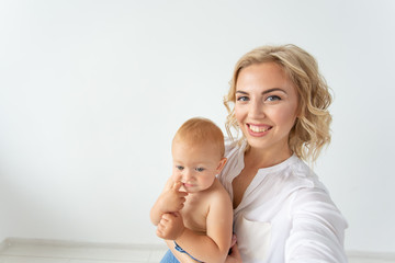 Cute little baby girl and her mother taking selfie in a living room.