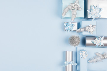 Airy soft cold winter season celebration background in pastel blue and silver color with different gift boxes as decorative border, top view.