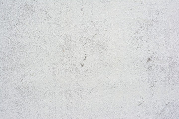 Concrete wall texture with small cracks carelessly painted with white paint