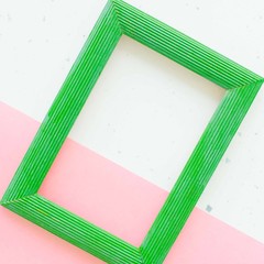 Wooden green photo frame on white and pink background