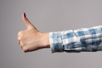 Woman showing thumbs up gesture isolated gray background.