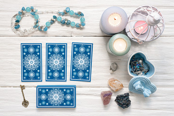 Blue tarot cards and key to the fate on white wooden table background. Clue to the fate concept.