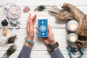 Fortune teller woman and a blue tarot cards over white wooden table background.