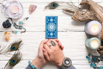 Fortune teller woman and a blue tarot cards over white wooden table background.