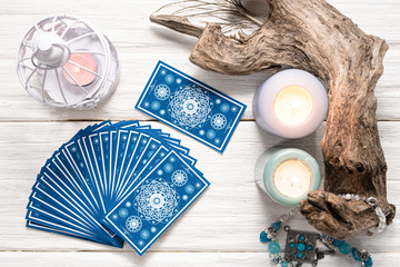 Fortune teller woman and a blue tarot cards over white wooden table background.