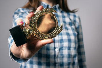 Winner is showing a golden medal in hand isolated on a gray background.