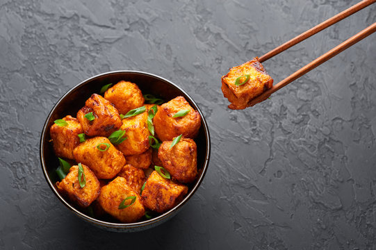 Paneer Manchurian or Paneer 65 in bowl at black concrete background. Paneer Manchurian is Indian Chinese cuisine dish with panner cheese, tomatoes, onion, soy sauce. Copy space