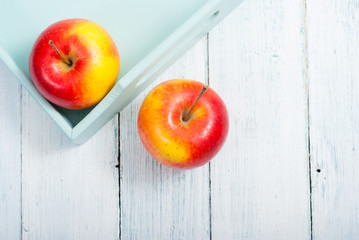 apples at blue tray, white wood table
