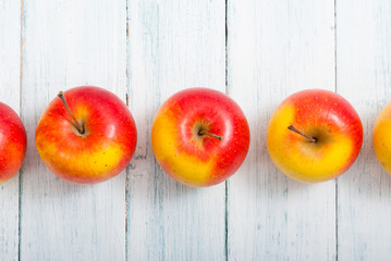 apple fruits in a row, white wooden table background