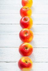 apple fruits in a row, white wooden table background