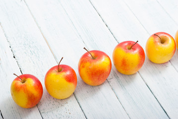 apple fruits in a row, white wooden table background