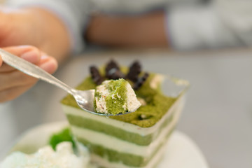 People using a spoon to scoop the green tea cake