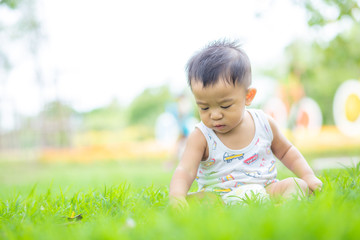 Adorable little boy sitting in green park field