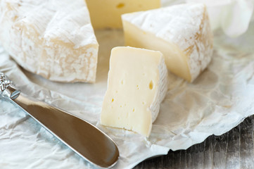 Gourmet spicy Camembert cheese, brie on white paper background with cheese knife. Spicy appetizer for gourmets. Selective focus