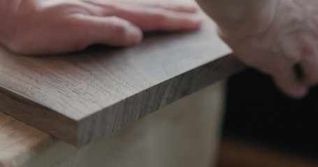 Fototapeta na wymiar woodworker hand sanding walnut board with sand block