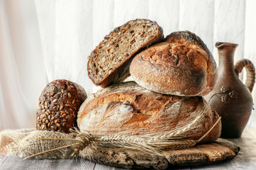 Beautiful loaves of bread on a leaven of white wheat on a plate on the edge of the canvas. Homemade cakes, handmade. Close up