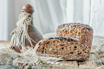Beautiful loaves of wheat leaven bread with an assortment of grains and seeds on a plate on the edge of the canvas. Homemade cakes, handmade. Close up. Lifestyle