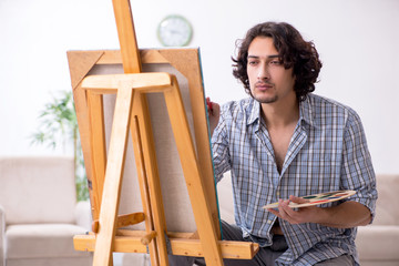 Young handsome man enjoying painting at home