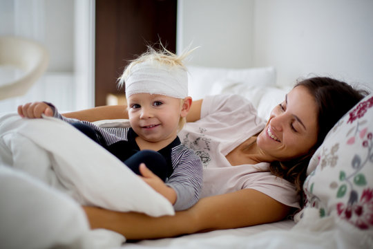 Little Toddler Boy With Head Injury, Lying With Mom In Bed, Tired