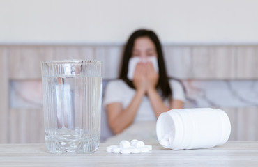 Flu medicine woman Infected With Cold the drug is placed on the table and a glass of water.
