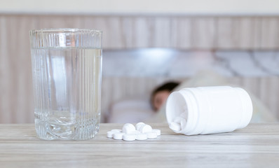 Flu medicine woman Infected With Cold the drug is placed on the table and a glass of water.