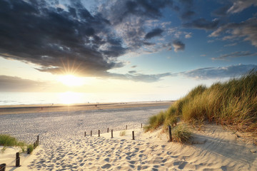soleil couchant sur le chemin de sable vers la plage de la mer du Nord