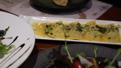 Eating Italiand cuisine ravioli and salad set on table