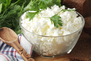 A bowl with cottage cheese, a bunch of green and rye bread
