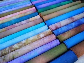 Rolls of colorful fabrics. Dyed fabric for sewing. Cross stitch fabric