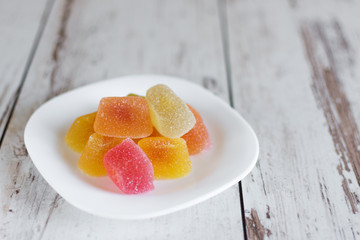 Composition with colorful marmalade candies on wooden background closeup.