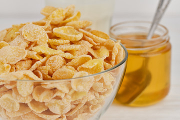 Corn flake in a bowl, honey in jar near. on white background, 