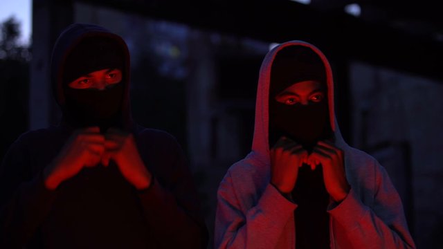 Black teenage bandits putting on balaclava, dangerous young criminals, security