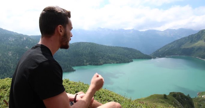 Young man during a hike eats blueberries for a short break. Filmed in the Ritom Lake in Switzerland filmed in slow motion.