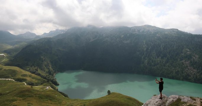 Backpacker enjoying the view and record a video of the famous Lake Ritom in Switzerland.
