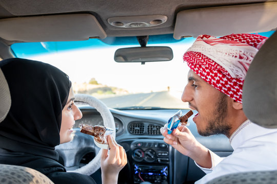 Two arqabic people eating chocolate in the car