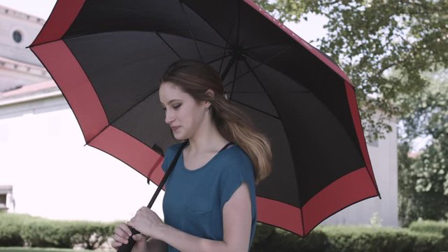 Young woman walks in the city with a black and red umbrella