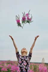 Pregnant girl walking in field of flowers fireweed, woman smiling and picking flowers. The girl is...
