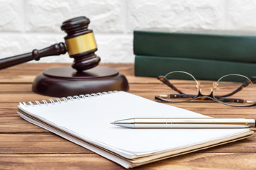 Notepad with judge gavel and books at the workplace.