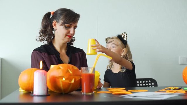 Little Girl and her Mom Making Halloween Crafts from Orange Plastic Cups. Holidays and Halloween Decorations Concept