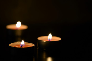 Three burning candles close up in the darkness. Mystery background