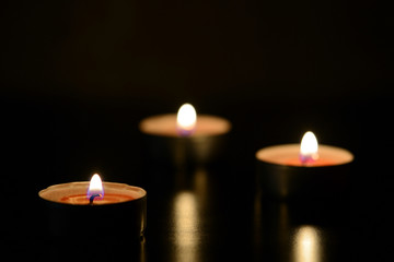 Three burning candles close up in the darkness. Mystery background