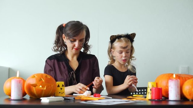 Little Girl with Mother Making Halloween Crafts from Paper to Decorate their Home. Holidays and Halloween Decorations Concept