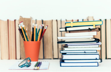 Fototapeta premium Notebooks piles, stack of books education back to school background, textbooks, glasses and pencils in holder with copy space for text.