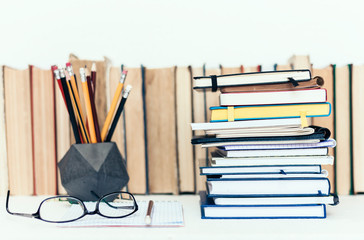 Notebooks piles, stack of books education back to school background, textbooks, glasses and pencils in holder with copy space for text.